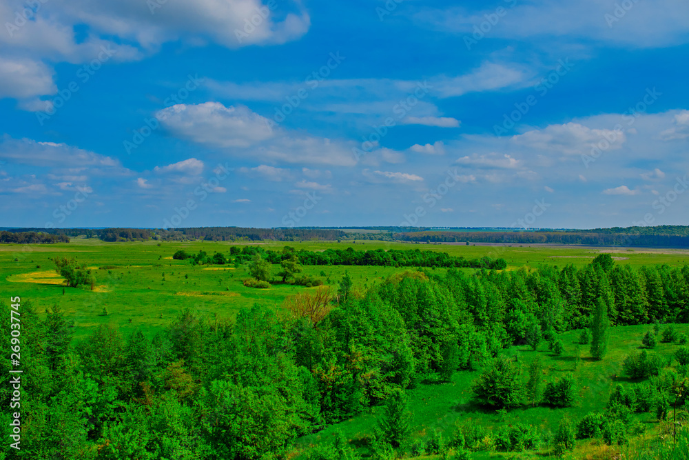 green fields and forests against a blue sky with clouds green fields and forests against a blue sky with clouds