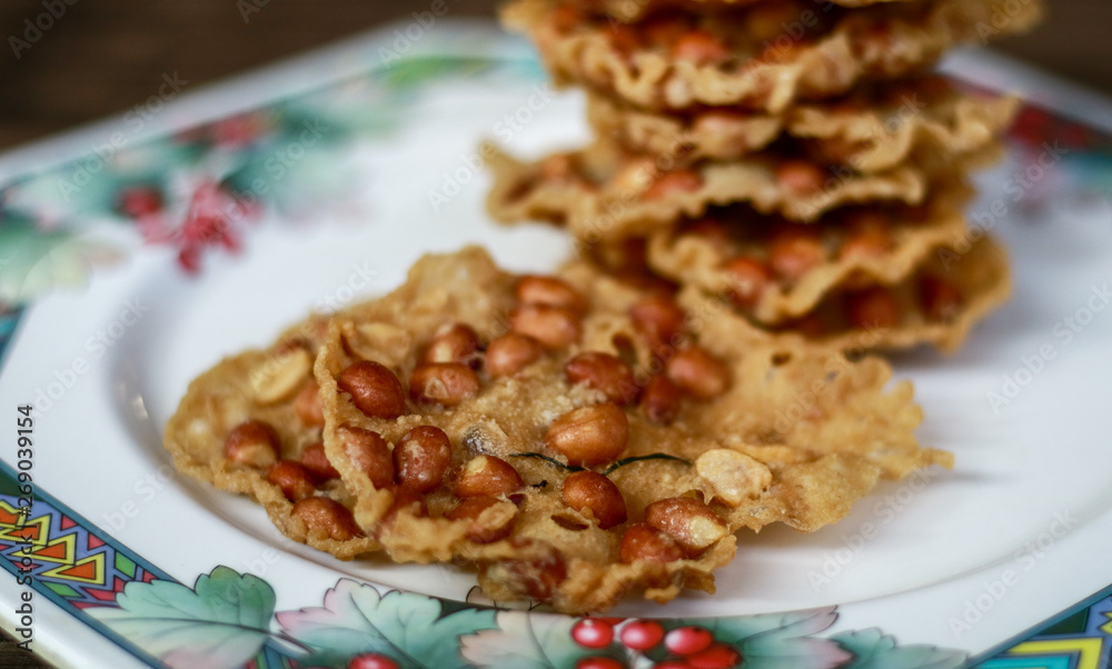 Peanut Peyek on plate. Peanut Rempeyek or Peyek is a deep-fried savoury Javanese cracker made from rice flour with peanut by crispy flour batter. Indonesian food. Peanut Peyek on plate. Peanut Rempeyek or Peyek is a deep-fried savoury Javanese cracker made from rice flour with peanut by crispy flour batter. Indonesian food.