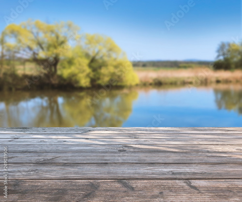 spring background with wooden terrace, blurred soft light with see and trees. product display template / presentation. Mock up template for display.