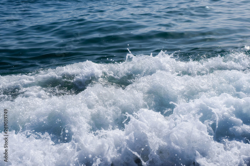 White Foam Of Sea Waves, Splashes Ashore. Blue Sky. Hot Summer.