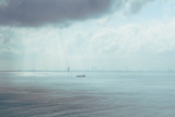 Panorama View of a storm coming on the ocean, storm clouds on the horizon with ray light, cargo ship and city on background