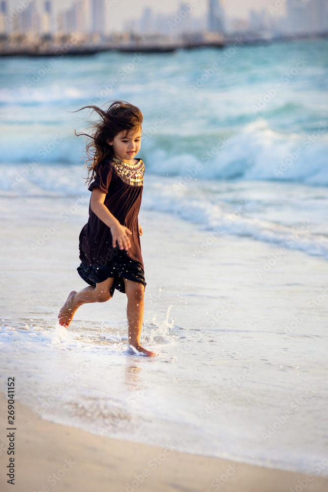 Young girl running along the beach in Dubai Young girl running along the beach in Dubai