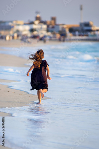 Young girl running along the beach in Dubai