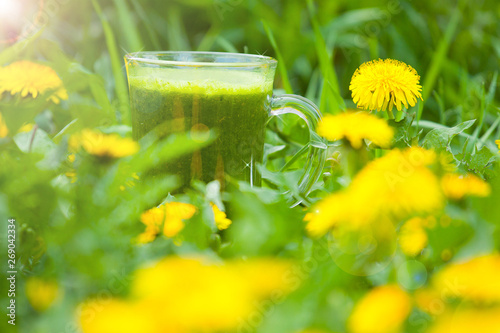 Green herbal smoothie on the lawn with dandelions