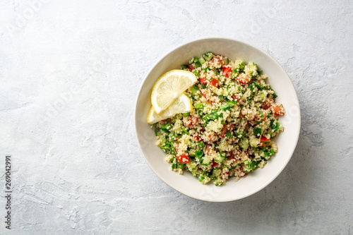 Traditional Arabic Salad Tabbouleh with couscous, vegetables and greens on concrete background. Top view. Copy space.