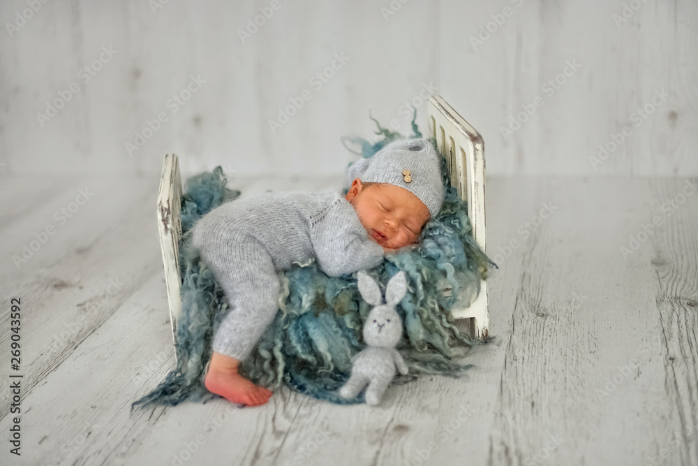 A newborn baby boy is sleeping on a little cot in the first days of life  - obrazy, fototapety, plakaty 