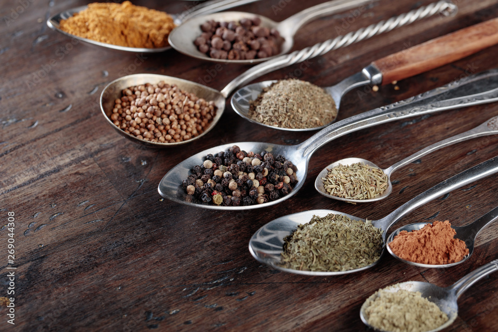 Different spices in spoons on a wooden background. Different spices in spoons on a wooden background.