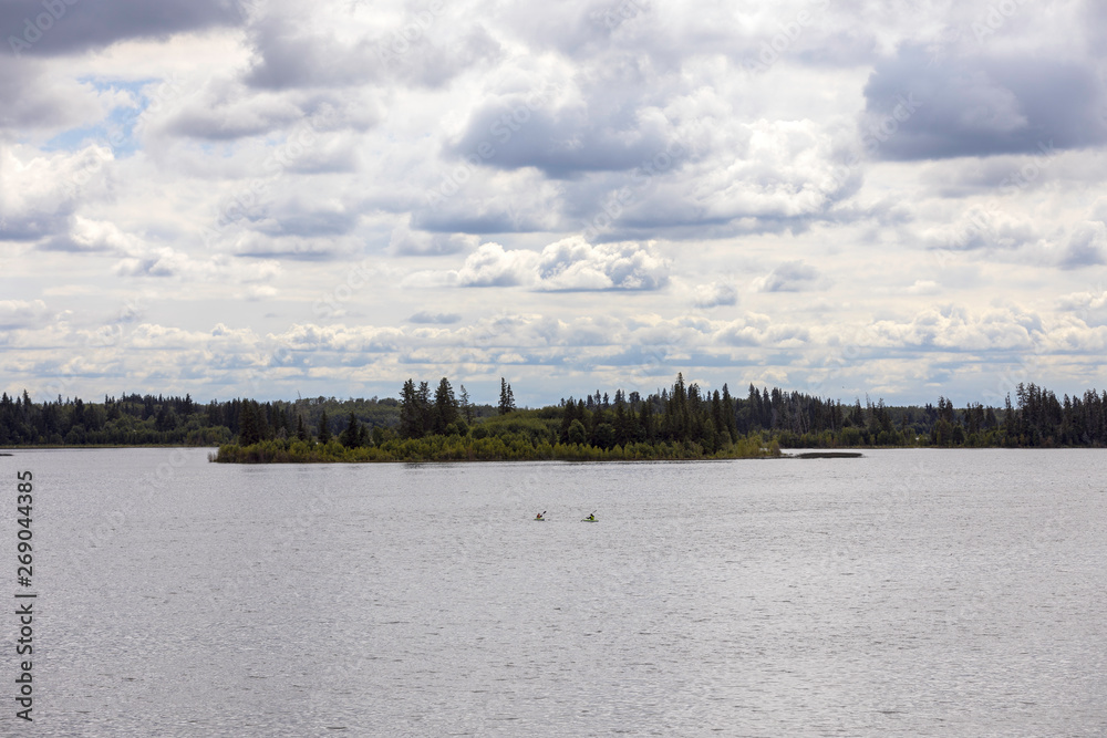 A middle age couple kayaking in the distance, on Astotin Lake, Elk Island National Park, Alberta, Canada.