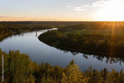 Beautiful sun rays of the setting sun over the North Saskatchewan River and Terwillegar Park Footbridge in Edmonton, Alberta, Canada