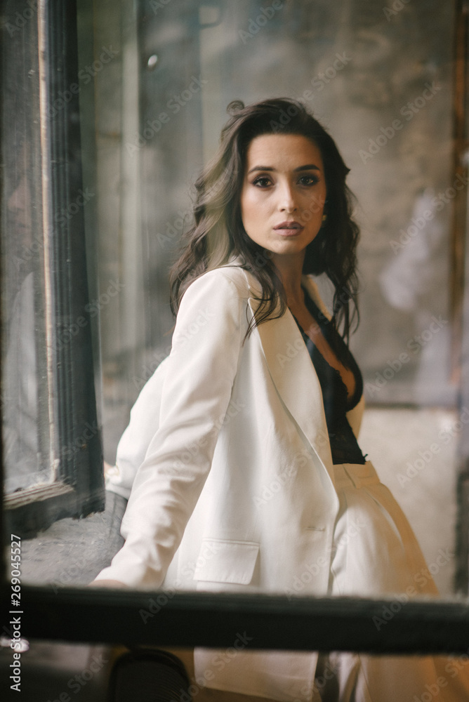 Fototapeta premium Young brunette woman posing in a suit by the window