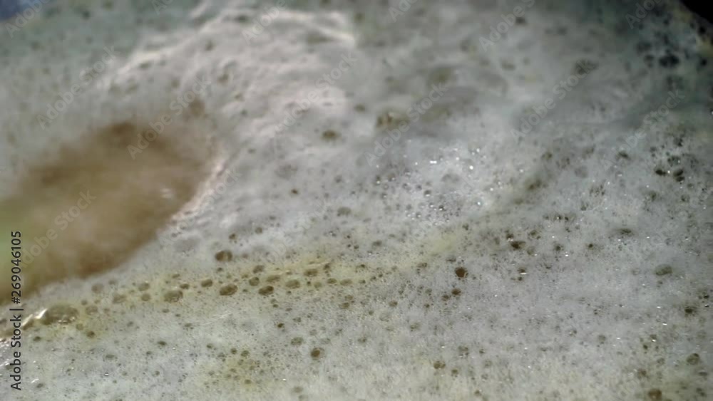 Small colorful bath bomb lies in the tub and dissolves. On the surface of the water traces of aromatic oil. Small colorful bath bomb lies in the tub and dissolves. On the surface of the water traces of aromatic oil.
