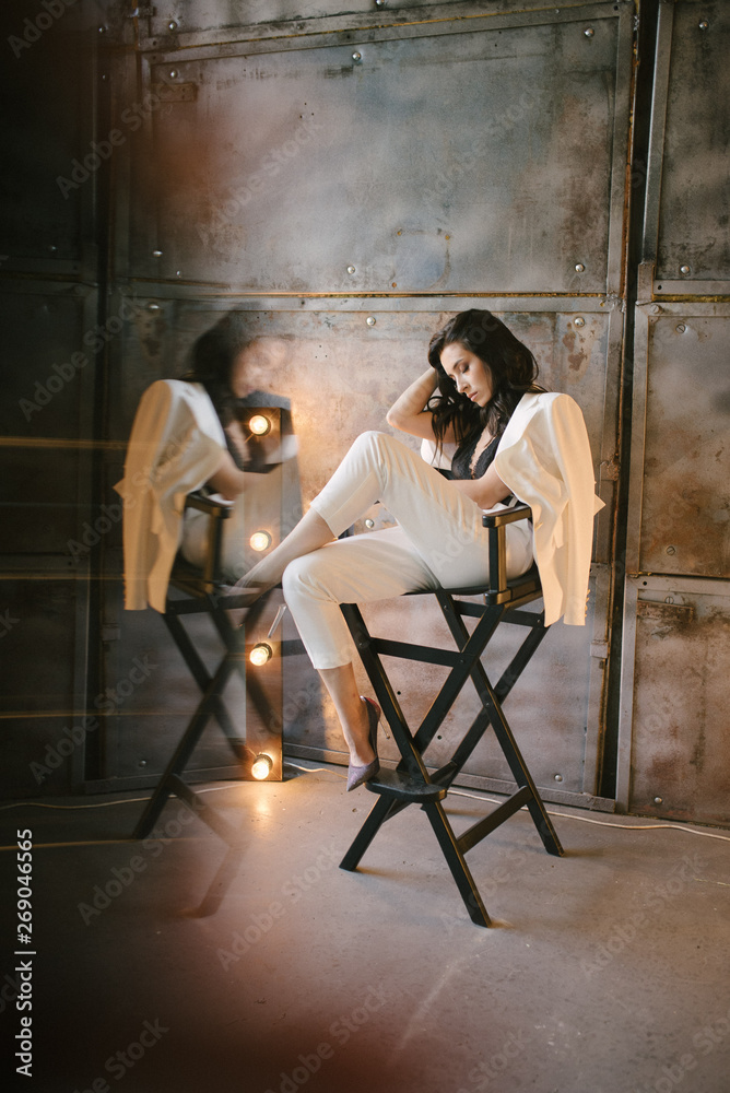 Young brunette woman posing in a suit sitting on a sofa Young brunette woman posing in a suit sitting on a sofa