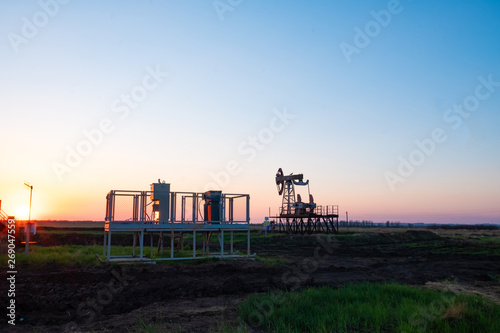Oil and gas production equipment running at sunset