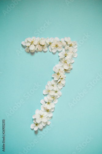 White flowers in the form of numbers on a blue sky background. Photo for design with place for text.