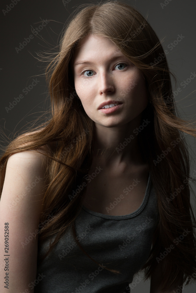 beautiful redhead model girl with long hair in the Studio on a gray background in a t-shirt beautiful redhead model girl with long hair in the Studio on a gray background in a t-shirt