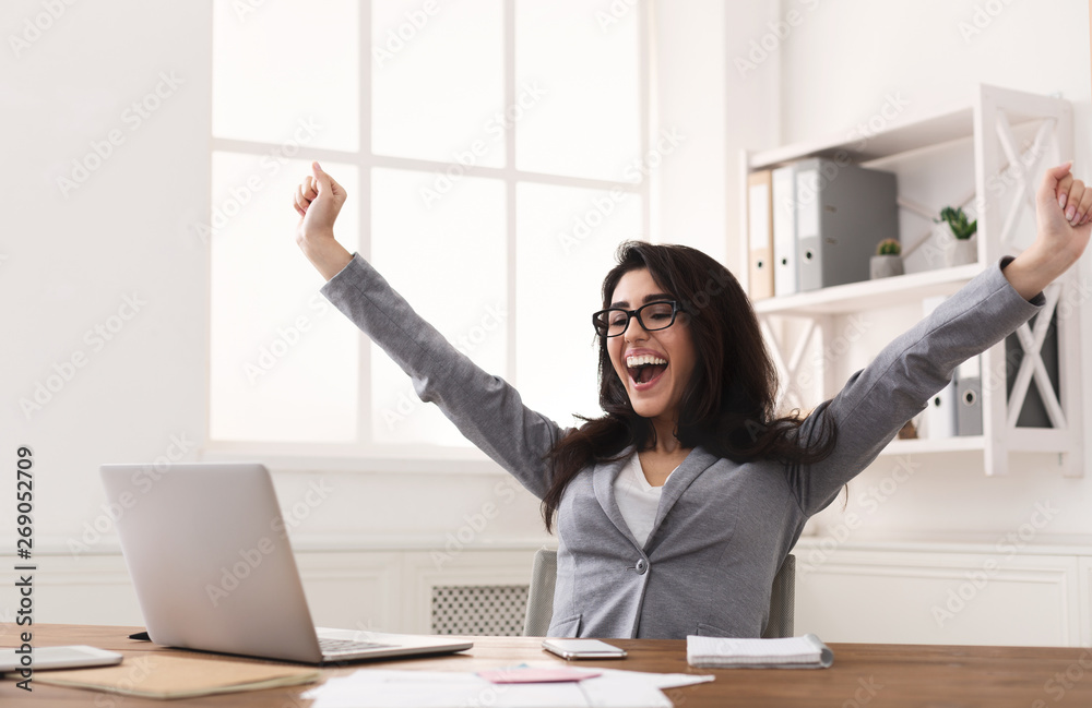 Excited Businesswoman Celebrating Success With Raised Hands At Workplace - obrazy, fototapety, plakaty 