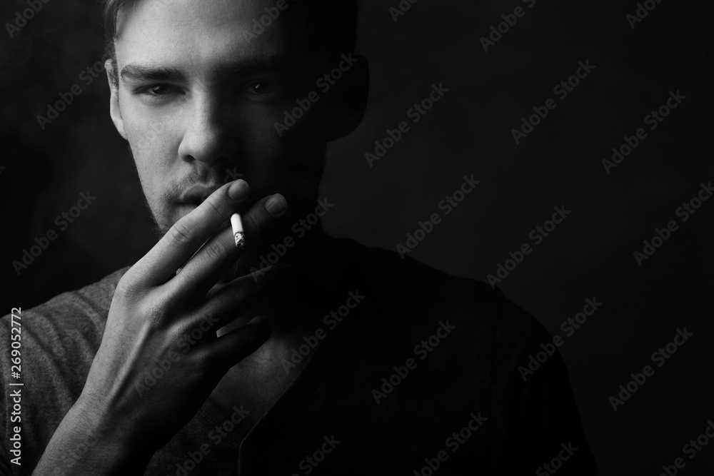 B lack and white portrait of a young Caucasian Smoking man with a short beard and mustache on a dark background, B lack and white portrait of a young Caucasian Smoking man with a short beard and mustache on a dark background,