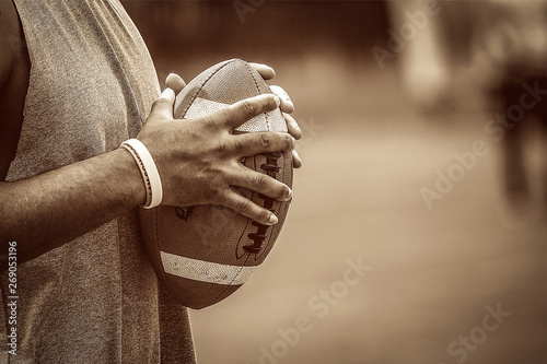 American football player holding the ball between his hands on a duotone brown color style