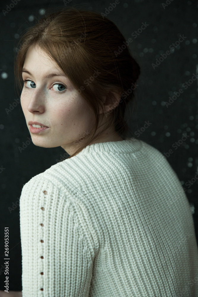 beautiful red-haired model girl in a sweater on a dark background beautiful red-haired model girl in a sweater on a dark background