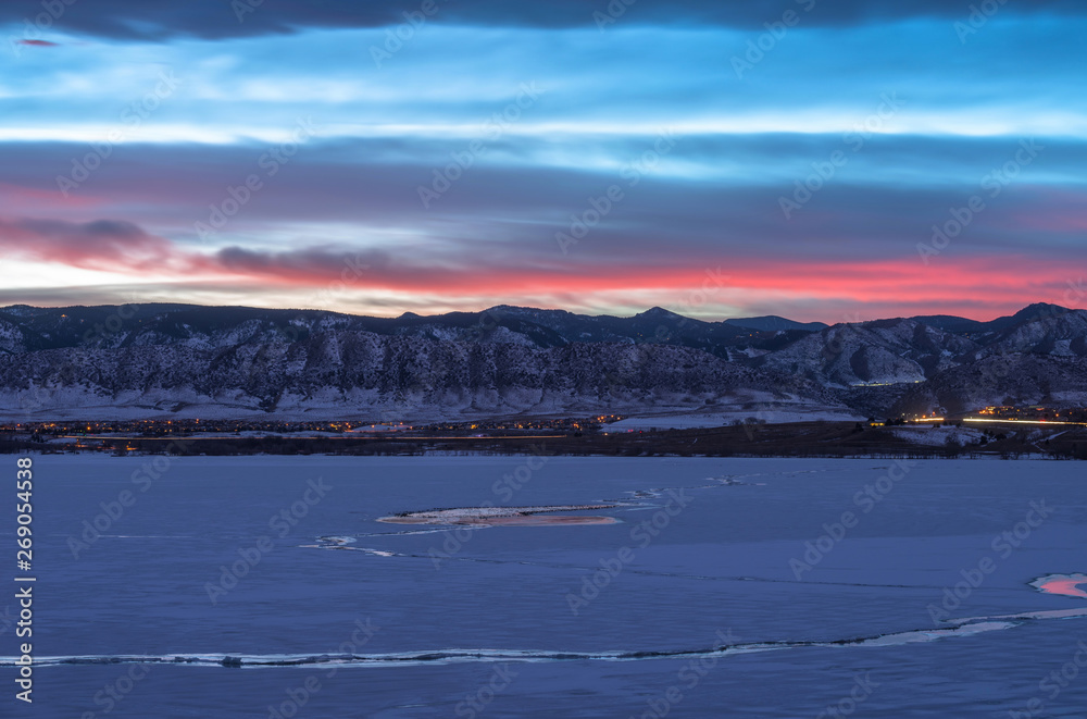 Winter Sunset at Denver Front Range - Sunset view of frozen lake and snow-covered mountains at southwest Denver, Colorado, USA.