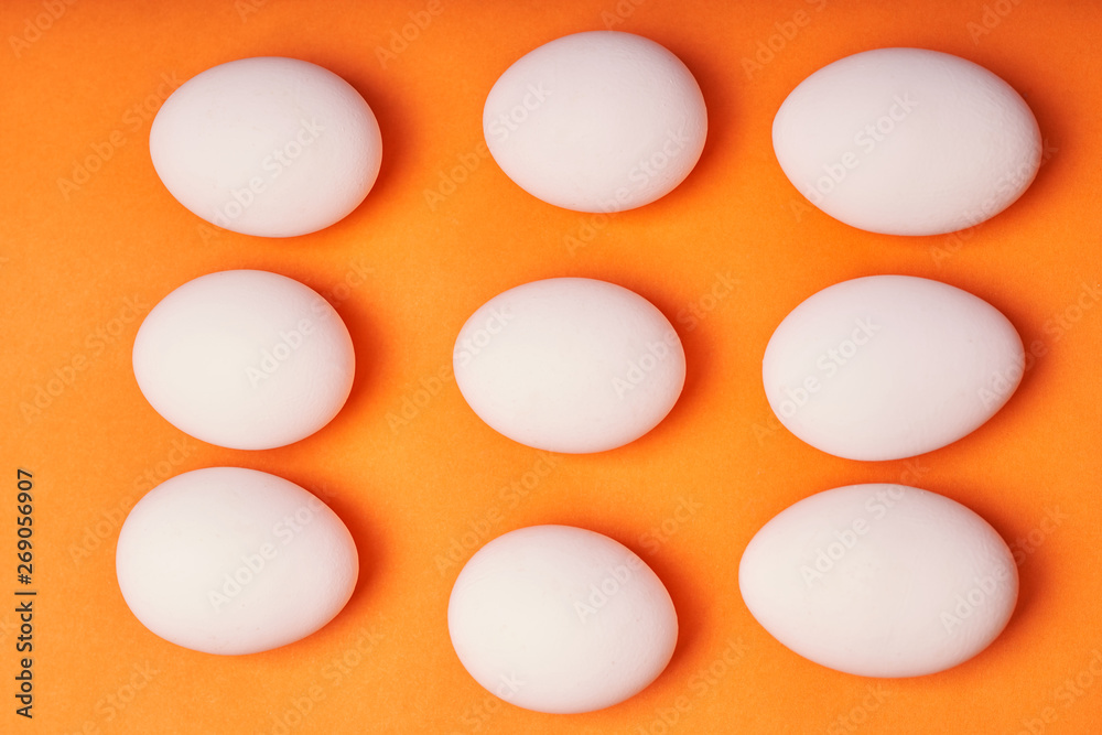 Chicken eggs laid out on an orange background