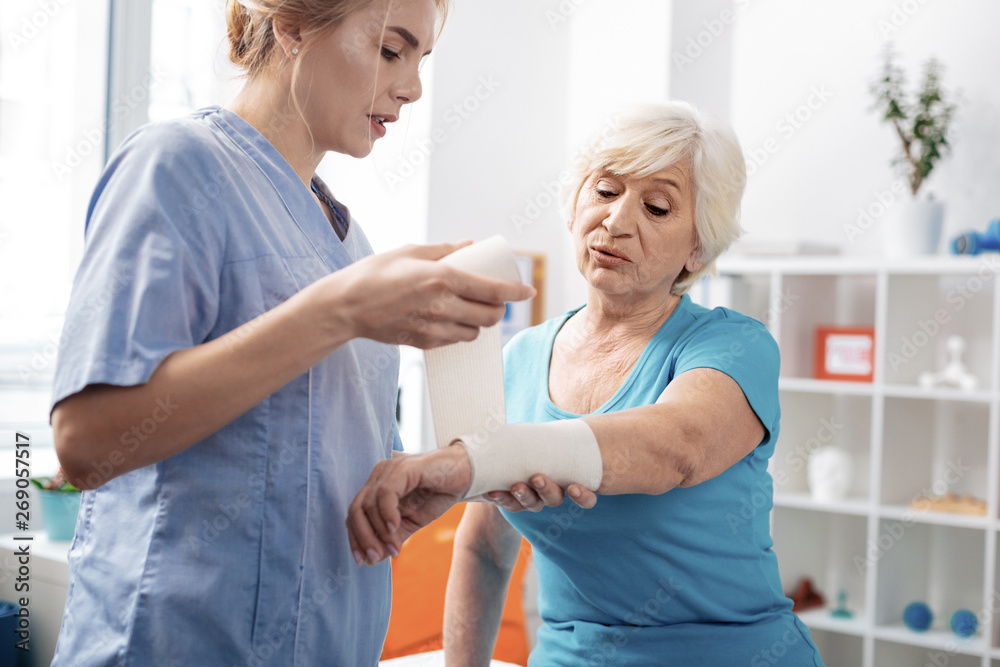 Fototapeta premium Nice professional nurse using the elastic bandage