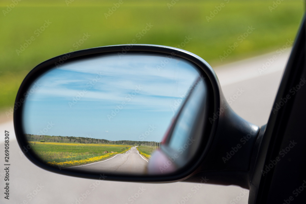 View of the highway in the side mirror of the car. Distance traveled.