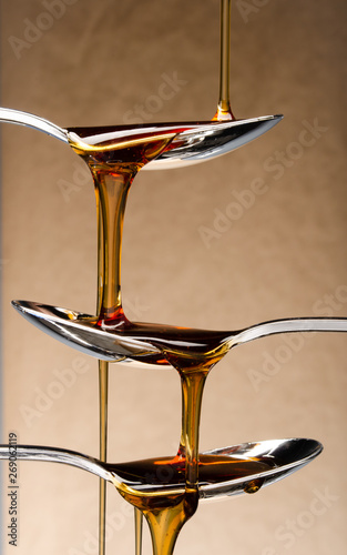 Honey dripping down three spoons