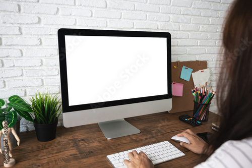 woman working empty screen computer on wood desk in home office.