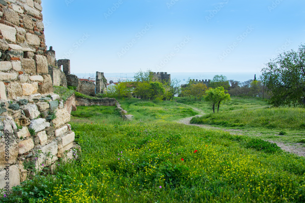 Footpath to the sea and poppies in the meadow and fortress wall of the Trigonion tower in Thessaloniki, Greece.
