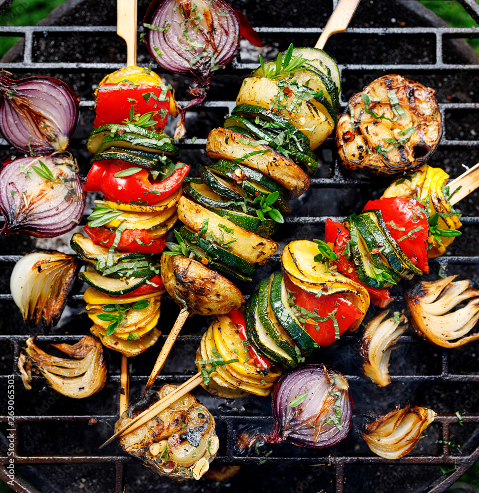 Vegetarian skewers, grilled vegetable skewers of zucchini, peppers and potatoes with the addition of aromatic herbs and olive oil on the grill outdoors. Grilled food