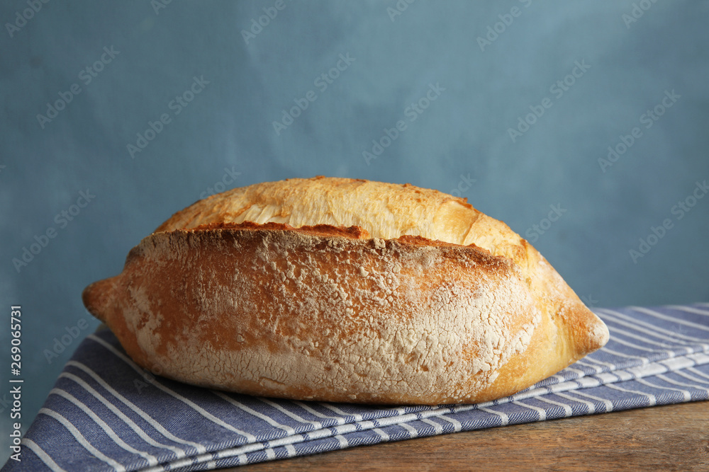 Fresh bread on table against color background