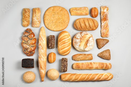 Different kinds of fresh bread on light background, flat lay