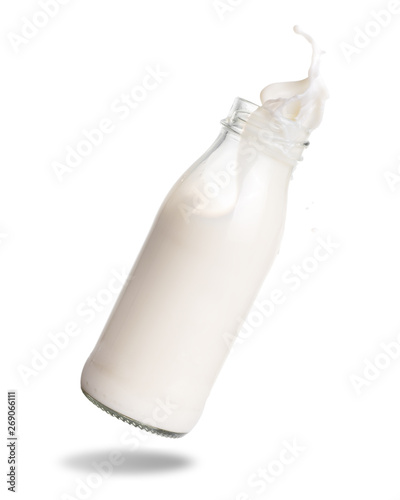 Milk splashing out of glass bottle isolated on white background.
