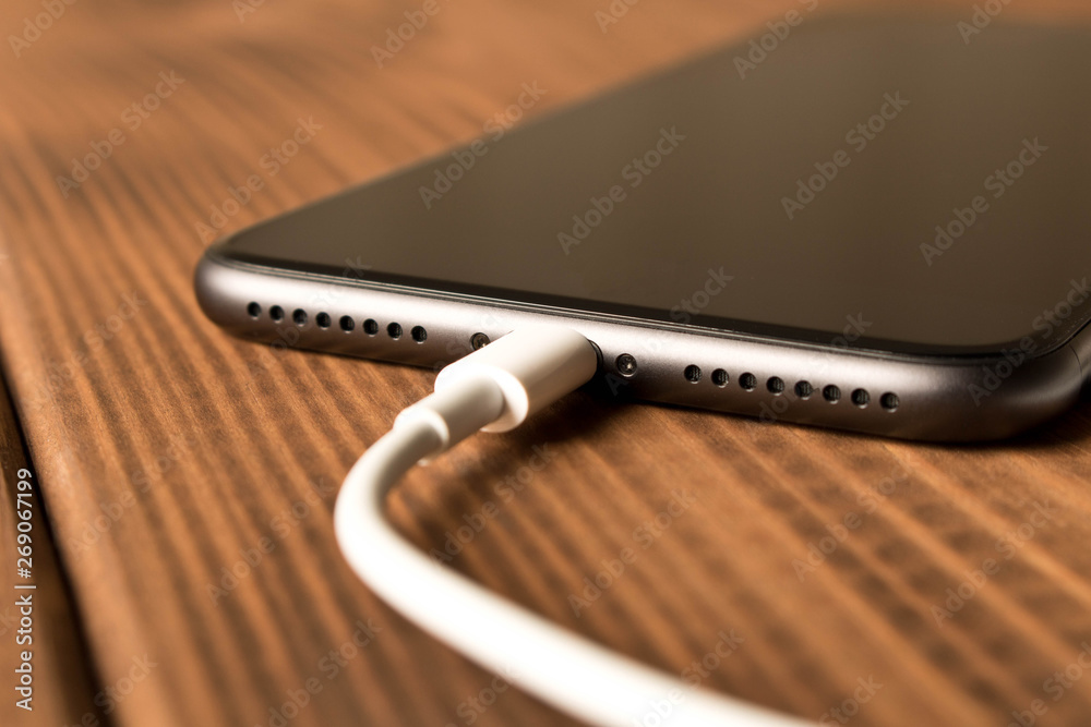 Smartphone on charge . On the wooden table . Close up. Smartphone on charge . On the wooden table . Close up.