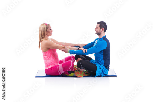 Happy young couple doing exercise in pair for pregnancy on the white background.
