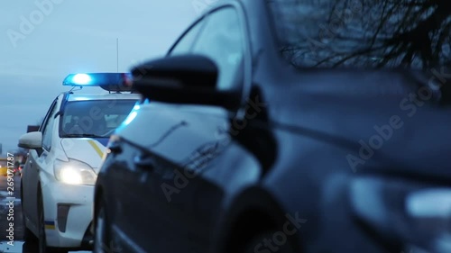 Close of the car fined for overspeeding standing on the roadside. Police car with lights turned on behind the driver. photo