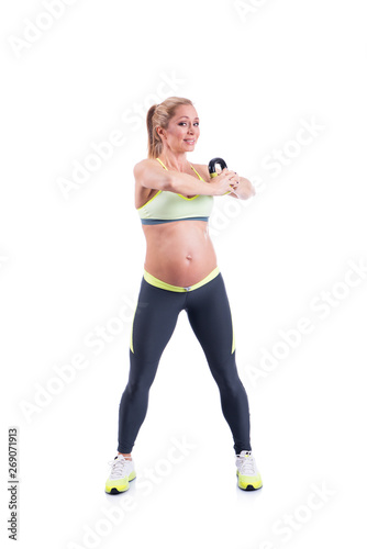 Beautiful happy pregnant women doing exercise with kettlebell on the white background