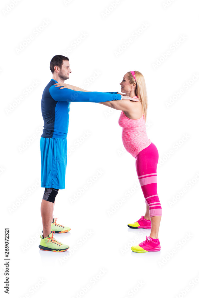 Happy young couple doing exercise in pair for pregnancy on the white background.