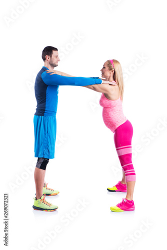 Happy young couple doing exercise in pair for pregnancy on the white background.