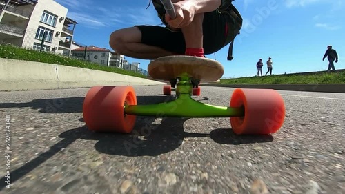 Active person skating on longboard. Closeup of skateboard wheels on asphalt road