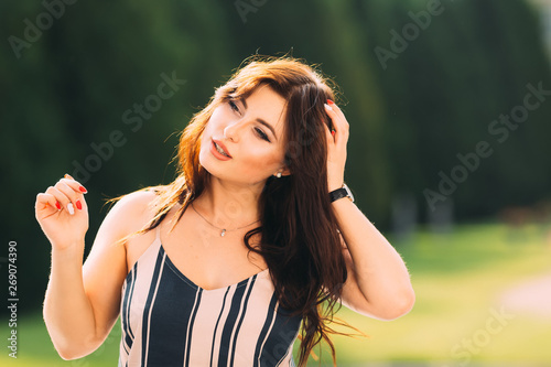 beautiful brunette woman holds her hand in her hair and says som