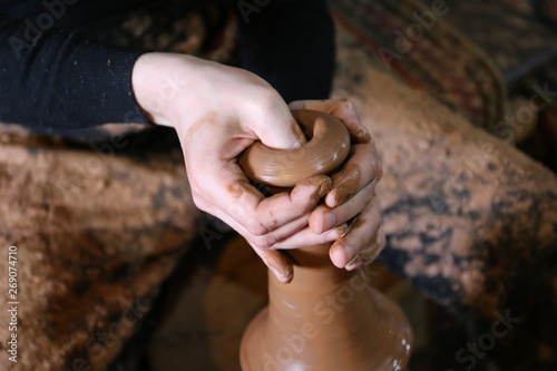 hands who makes on a potter's wheel a jug made of clay