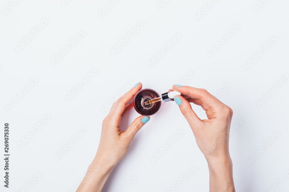 Top view female's hands holding bottle of cosmetic oil
