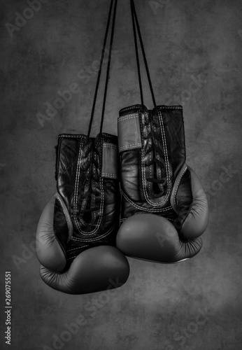  black boxing gloves hanging on the wall, close-up. © Lumppini