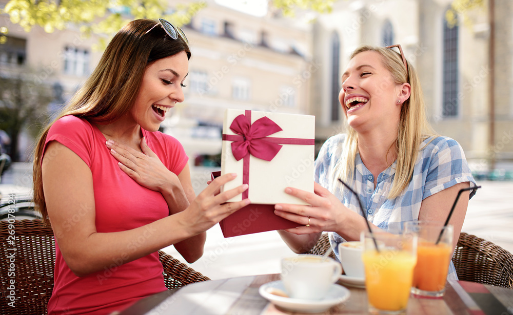 Birthday gift. Two beautiful girls celebrate birthday in the cafe. Consumerism, shopping, lifestyle concept