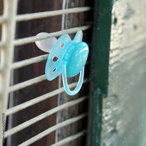 Blue baby pacifier stuck in a grate