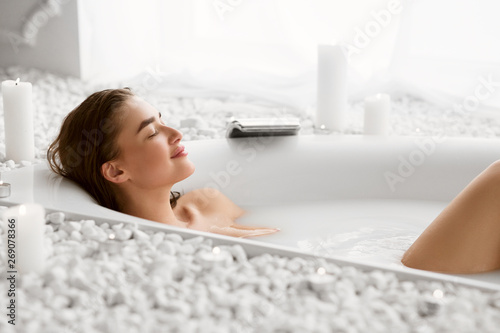 Fotografie, Obraz Beautiful Woman Relaxing In Milky Bathtub With Closed Eyes