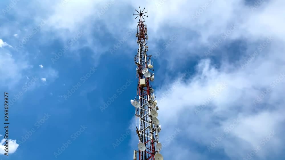 A telecommunication antenna with some clouds moving on the background on the blue sky A telecommunication antenna with some clouds moving on the background on the blue sky