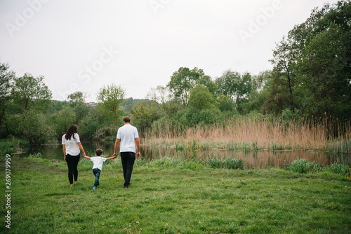 Happy family: mother father and child son on nature on sunset. Mom, Dad and kid laughing and hugging, enjoying nature outside. Sunny day, good mood. concept of a happy family © Serhii